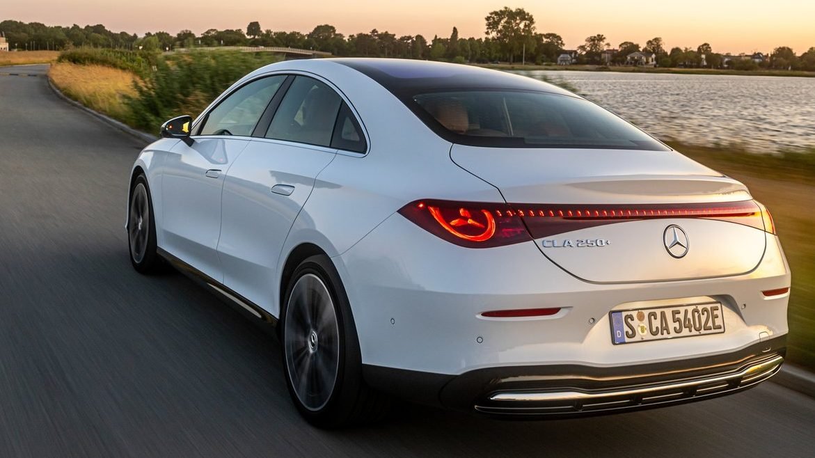 수변 도로를 주행하는 화이트 컬러 CLA 250+ 일렉트릭의 삼각별 LED 테일램프 및 후측면